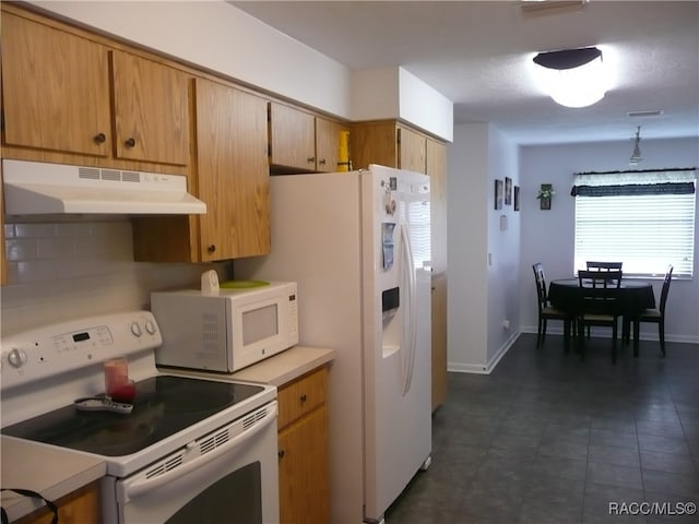 kitchen featuring decorative backsplash, white appliances, and dark tile patterned flooring