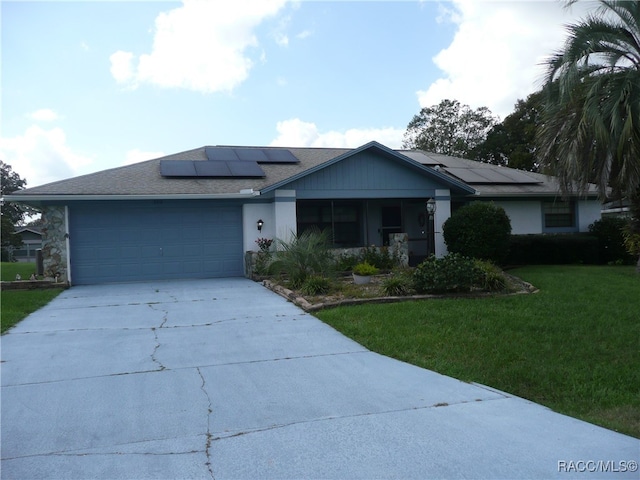 view of front of property with a front yard, solar panels, and a garage