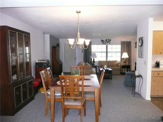 dining area with carpet and a notable chandelier