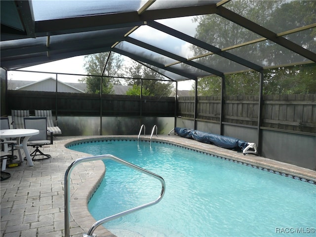 view of swimming pool featuring a lanai and a patio area