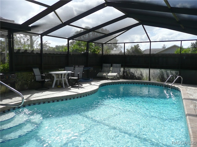 view of swimming pool featuring glass enclosure and a patio area