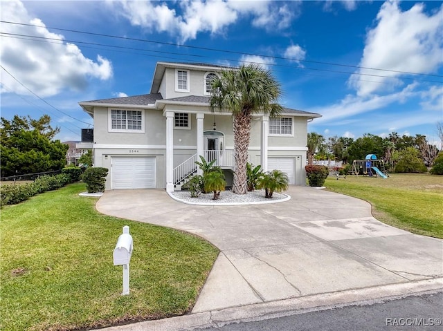 view of front of property with a garage, a front yard, a playground, and stucco siding