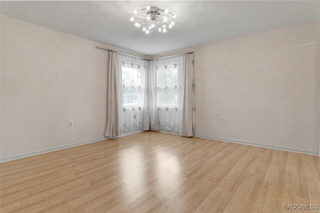 520 S Jefferson St, Beverly Hills, FL 34465 - spare room with baseboards, light wood-style flooring, and a notable chandelier