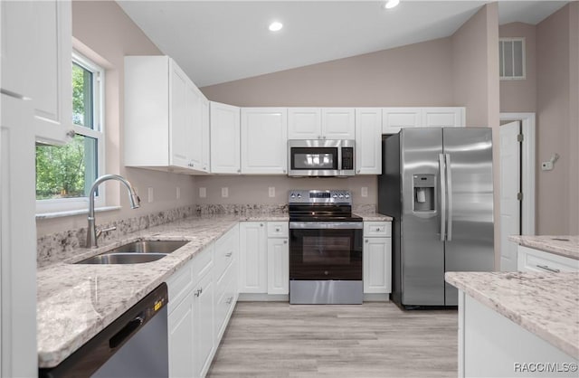 8880 N Circular Way, Citrus Springs, FL 34434 - kitchen with appliances with stainless steel finishes, white cabinetry, vaulted ceiling, light stone countertops, and light wood-style flooring