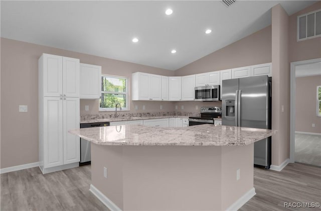 8880 N Circular Way, Citrus Springs, FL 34434 - kitchen featuring appliances with stainless steel finishes, light wood-style floors, a kitchen island, white cabinets, and light stone countertops