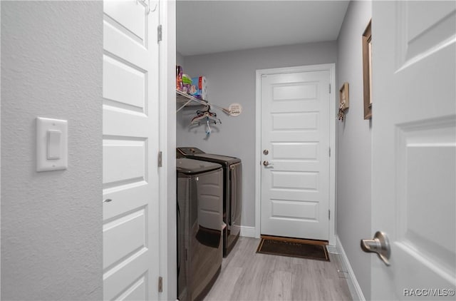 laundry room featuring separate washer and dryer and light hardwood / wood-style flooring