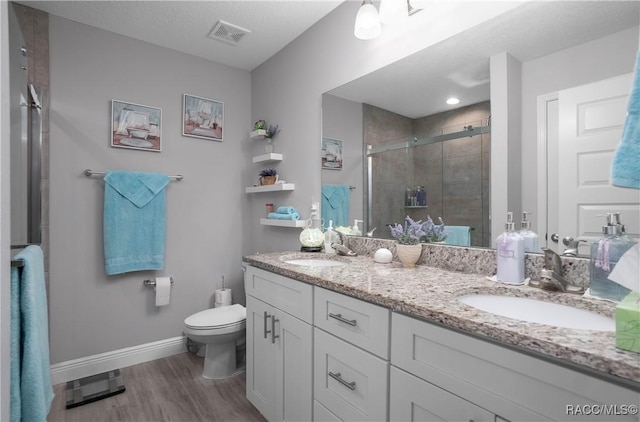 bathroom with vanity, a shower with door, toilet, and hardwood / wood-style floors