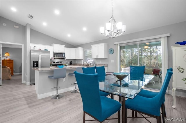 dining space featuring an inviting chandelier, light wood-type flooring, and vaulted ceiling