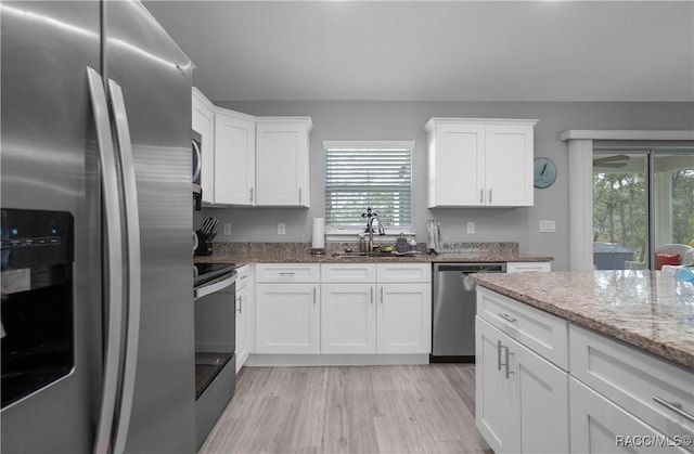 kitchen featuring sink, appliances with stainless steel finishes, white cabinets, and light stone counters