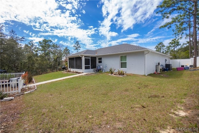 rear view of property featuring a lawn, a sunroom, and central AC unit