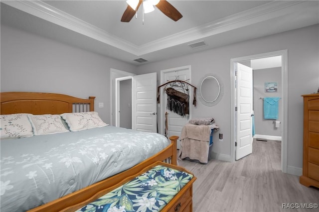 bedroom with ceiling fan, ornamental molding, light wood-type flooring, and a raised ceiling