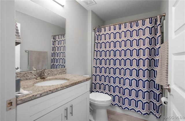 bathroom with toilet, vanity, a shower with curtain, and a textured ceiling