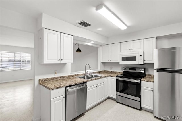 kitchen with stainless steel appliances, a sink, visible vents, white cabinetry, and pendant lighting