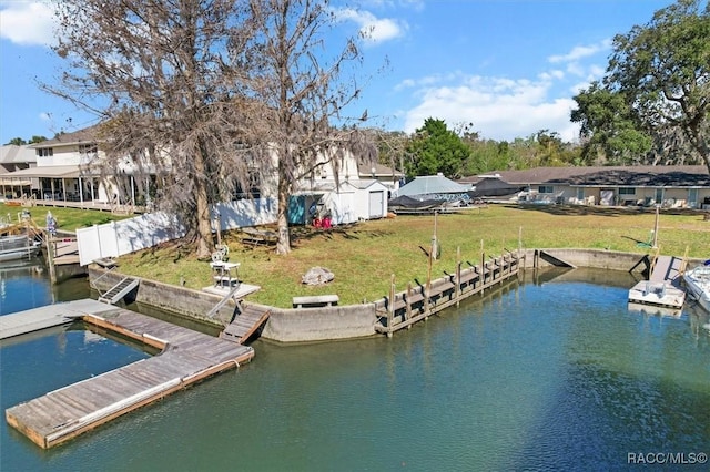 dock area with a yard, a water view, and fence