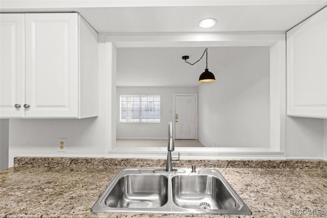 kitchen featuring hanging light fixtures, light countertops, a sink, and white cabinetry