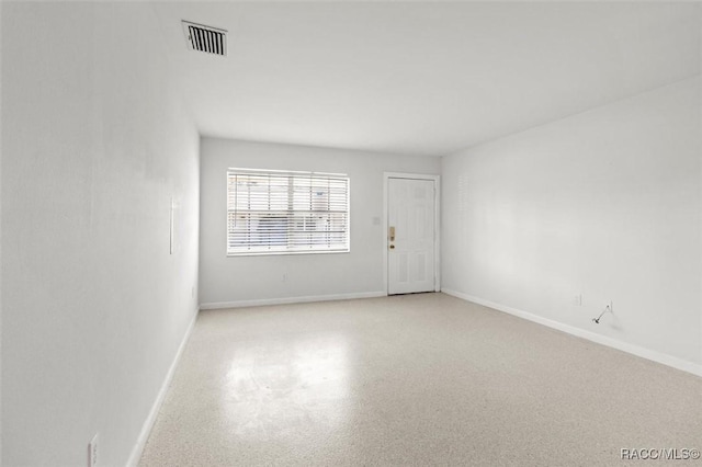 spare room with light speckled floor, visible vents, and baseboards