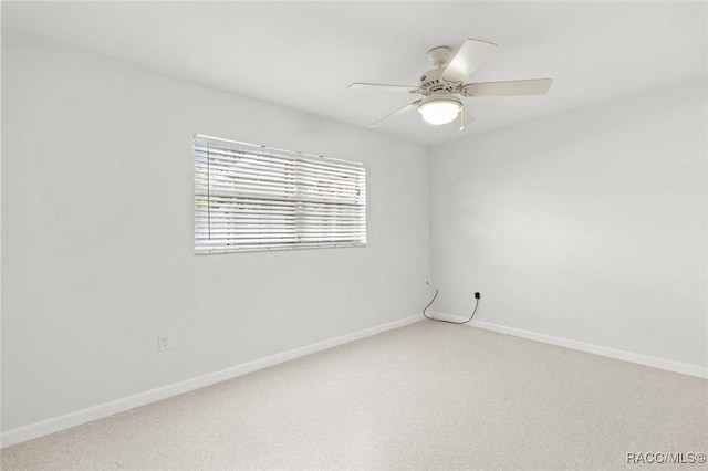 carpeted spare room with ceiling fan and baseboards