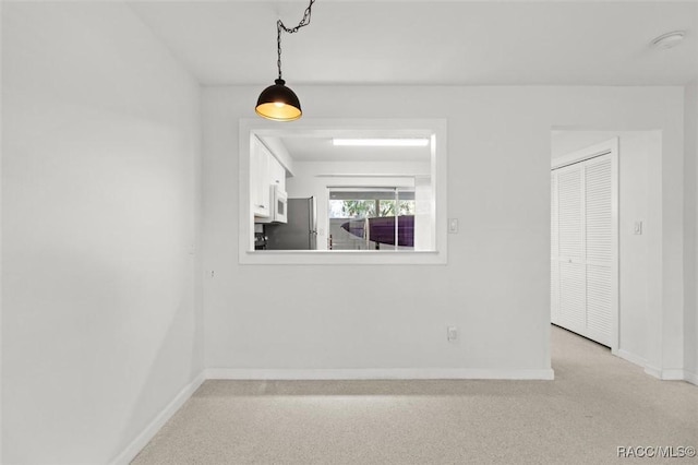 empty room featuring light colored carpet and baseboards