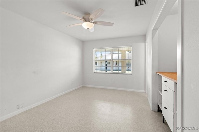 empty room featuring ceiling fan, visible vents, and baseboards