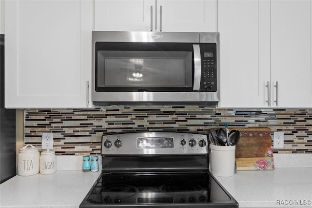 kitchen featuring white cabinets, stainless steel appliances, light stone counters, and tasteful backsplash