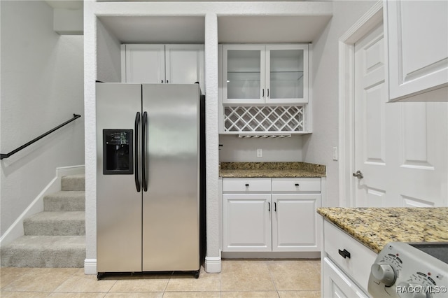 kitchen featuring white cabinets, stainless steel fridge, stone countertops, and light tile patterned flooring