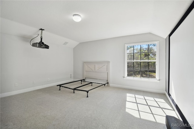 unfurnished bedroom with light colored carpet and lofted ceiling