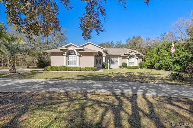 ranch-style home with stucco siding and a front yard