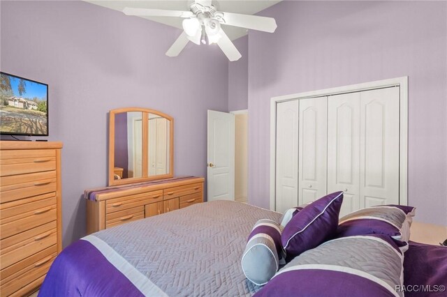 bedroom featuring a closet, a ceiling fan, and a towering ceiling