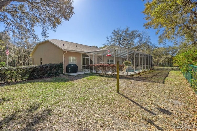 back of property with glass enclosure, a yard, an outdoor pool, stucco siding, and fence private yard