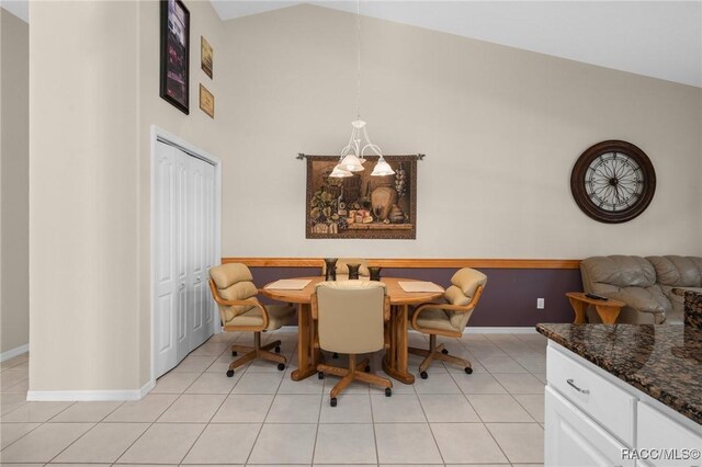 dining space with light tile patterned floors, baseboards, a notable chandelier, and high vaulted ceiling