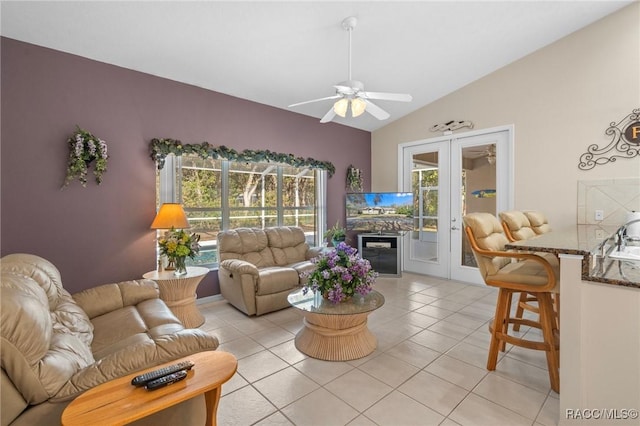 living room with a ceiling fan, vaulted ceiling, light tile patterned floors, and french doors