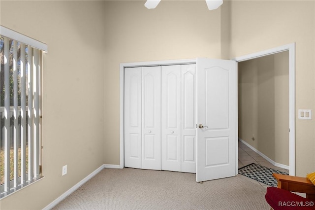 unfurnished bedroom with baseboards, multiple windows, light colored carpet, and a closet