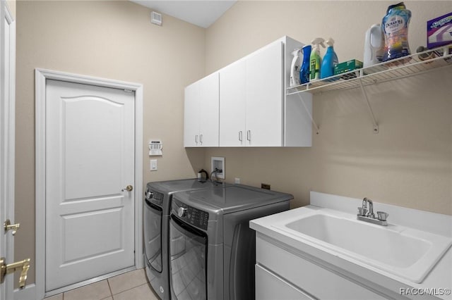 laundry room with a sink, light tile patterned floors, cabinet space, and washer and clothes dryer