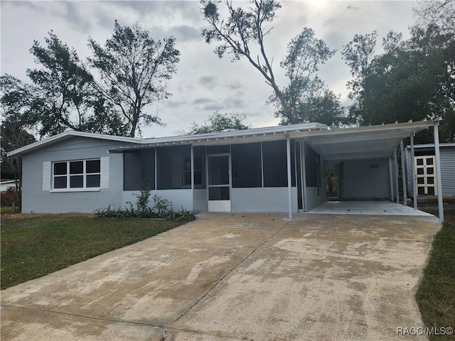 back of house with a lawn, a sunroom, and a carport