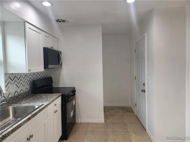 kitchen with sink, electric range, light tile patterned floors, tasteful backsplash, and white cabinetry