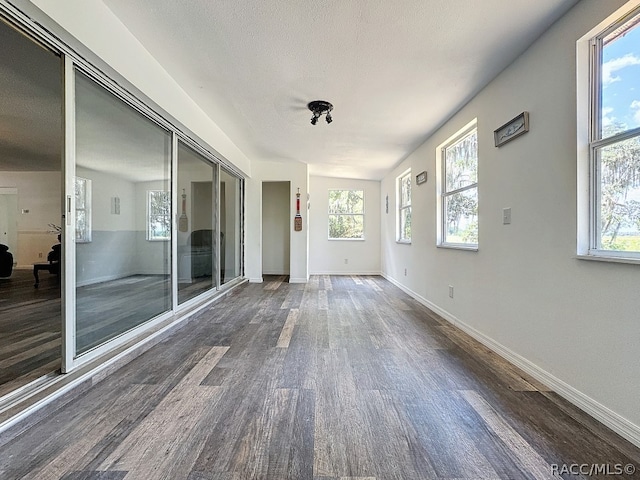 interior space with a textured ceiling, plenty of natural light, and dark wood-type flooring