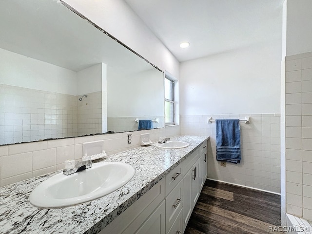 bathroom with tiled shower, vanity, hardwood / wood-style flooring, and tile walls