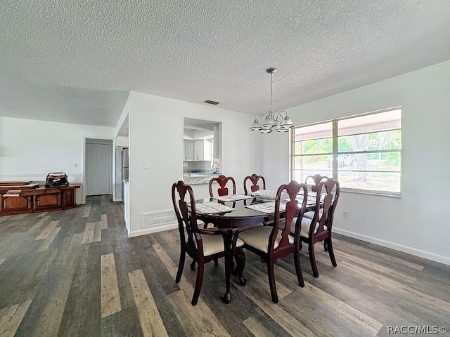 dining space with dark hardwood / wood-style flooring, a chandelier, and a textured ceiling