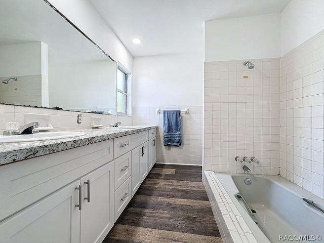 bathroom featuring vanity, wood-type flooring, tiled shower / bath combo, and tile walls