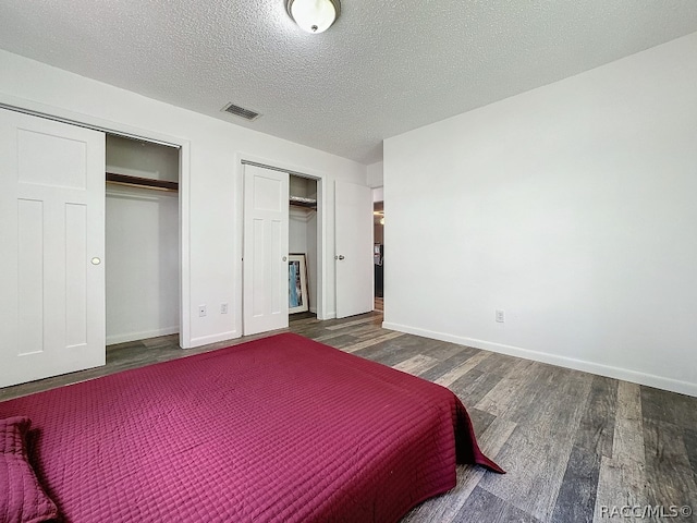 bedroom with a textured ceiling and dark hardwood / wood-style floors