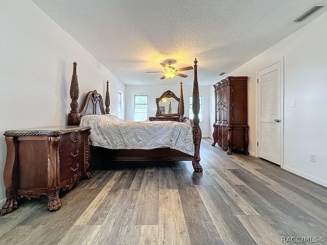 bedroom with a textured ceiling, dark hardwood / wood-style floors, and ceiling fan