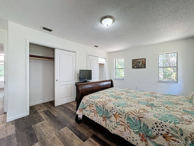 bedroom with multiple windows, dark wood-type flooring, and a textured ceiling