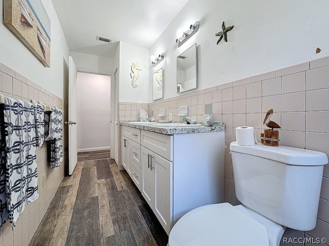 bathroom featuring vanity, toilet, wood-type flooring, and tile walls