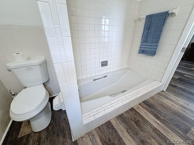 bathroom featuring a tile shower, wood-type flooring, tile walls, and toilet