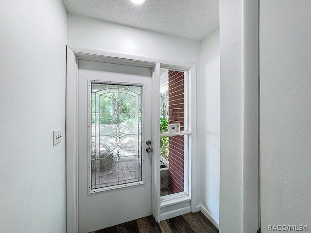 doorway with dark wood-type flooring and a textured ceiling