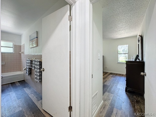 hall featuring a textured ceiling and dark hardwood / wood-style floors