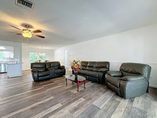 living room with ceiling fan, dark wood-type flooring, and a textured ceiling