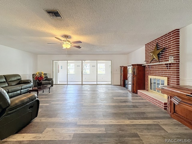 living room with a brick fireplace, ceiling fan, a textured ceiling, and hardwood / wood-style flooring