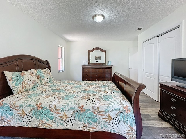 bedroom with a textured ceiling, light hardwood / wood-style flooring, and a closet