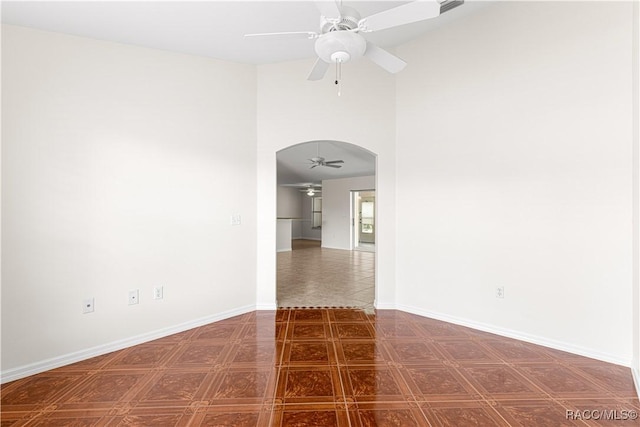 empty room with ceiling fan and a high ceiling
